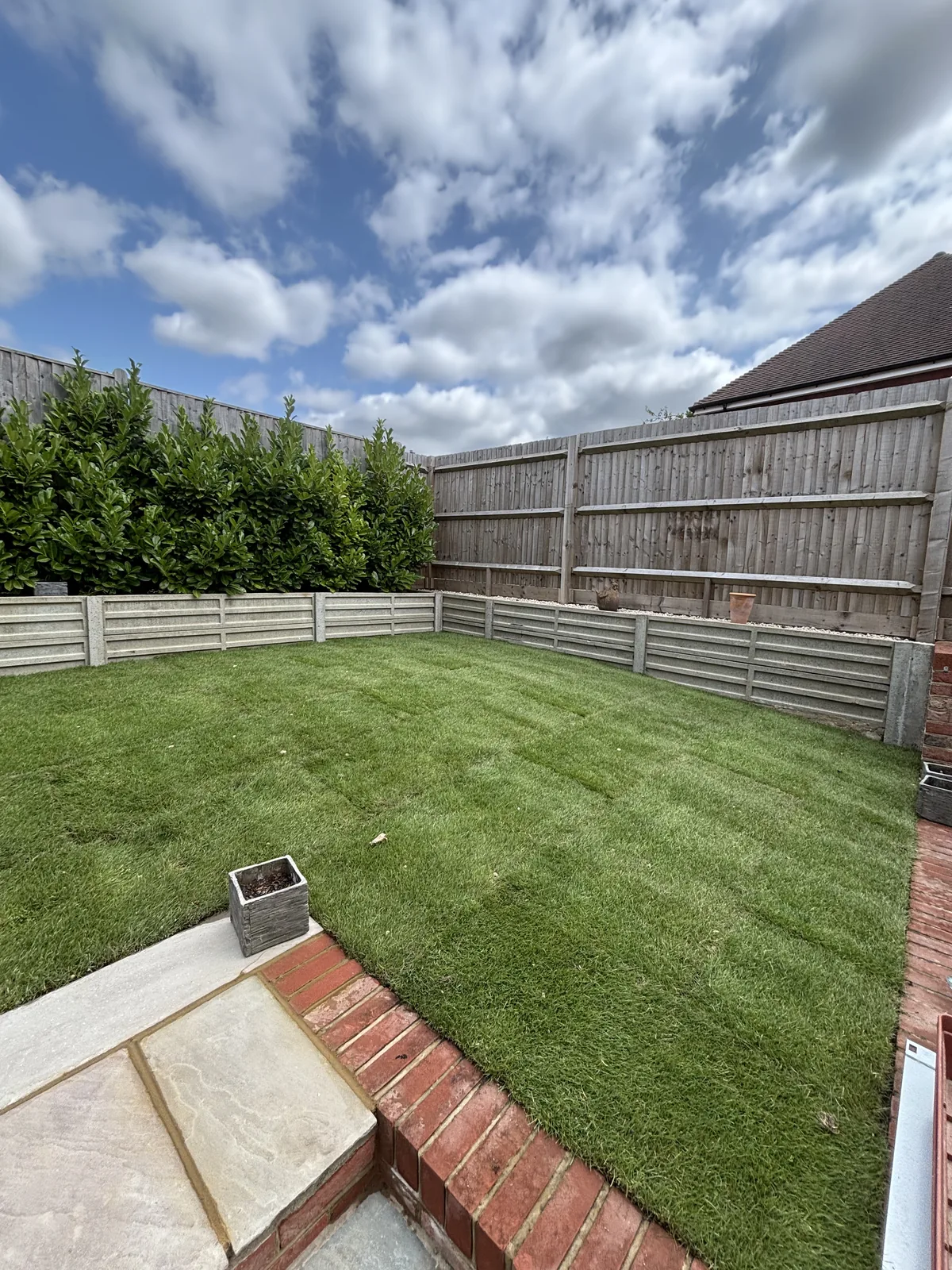 Level, freshly laid lawn framed by new Indian sandstone paving