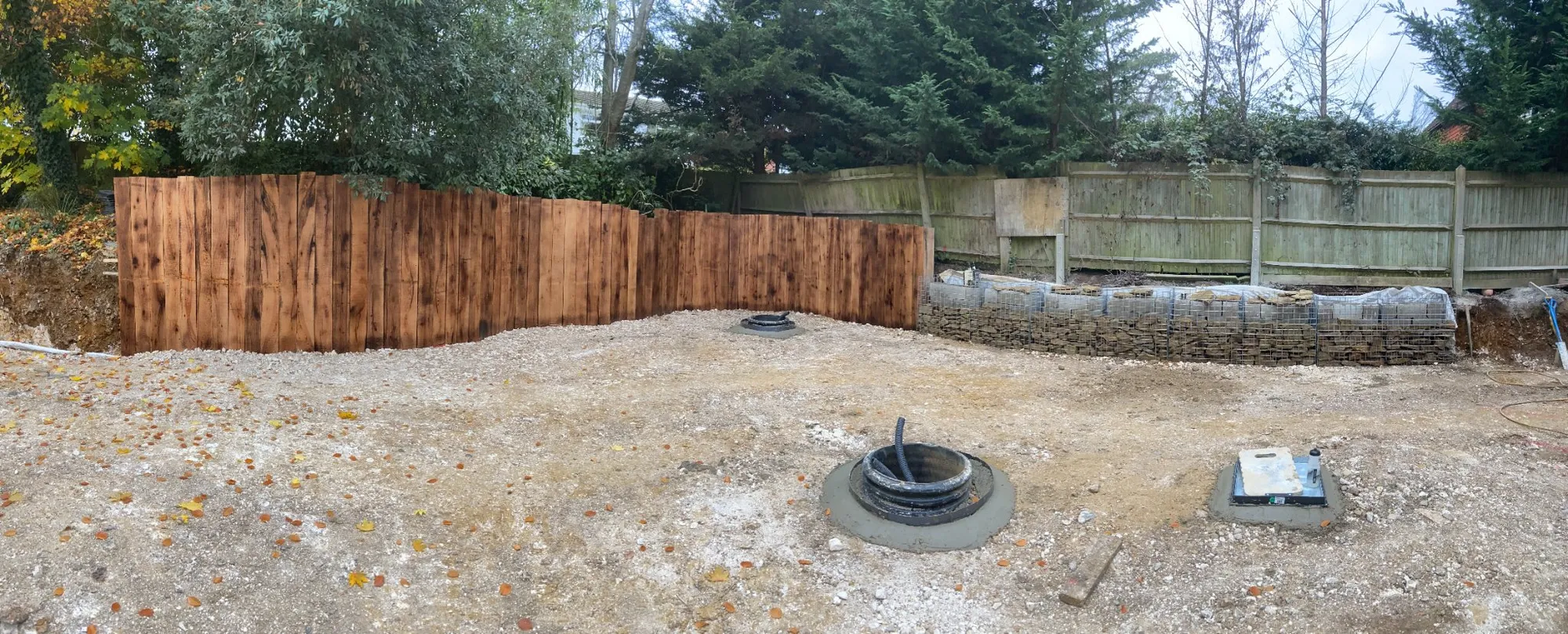 Curved upright oak sleeper retaining wall in a garden in Brighton and Hove